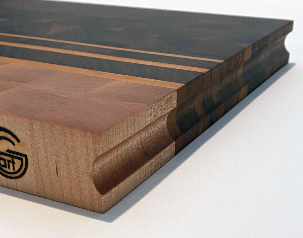 Oversized walnut and maple end grain cutting board with cherry accents and finger groove